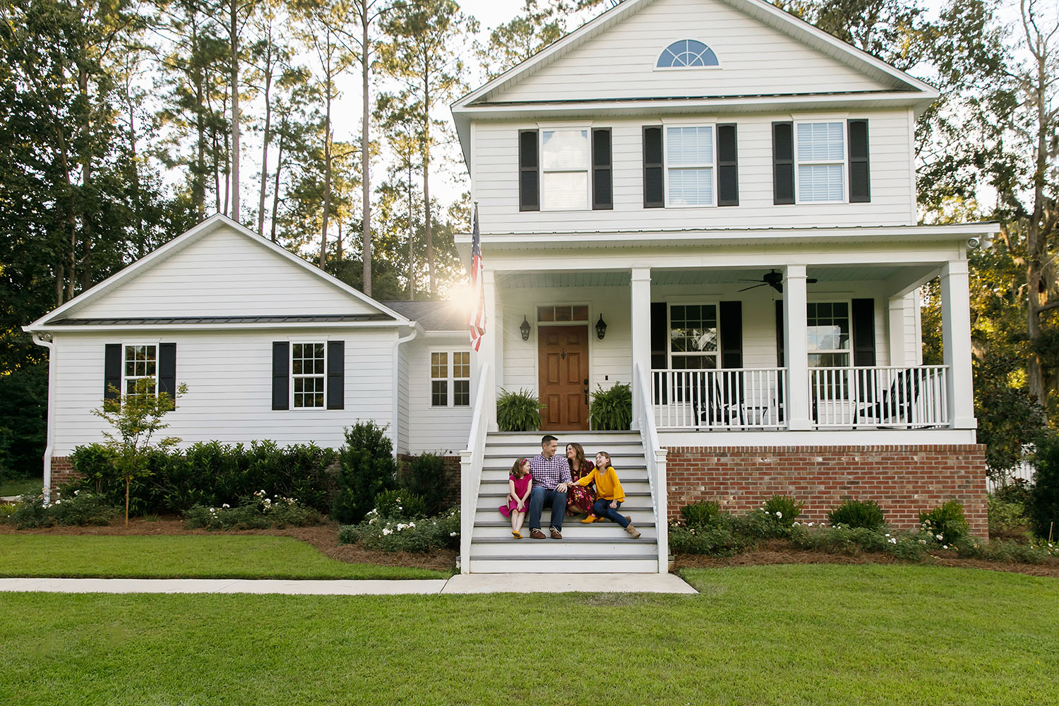 Family of Four With Daughters Sitting on the Steps Outside Their
